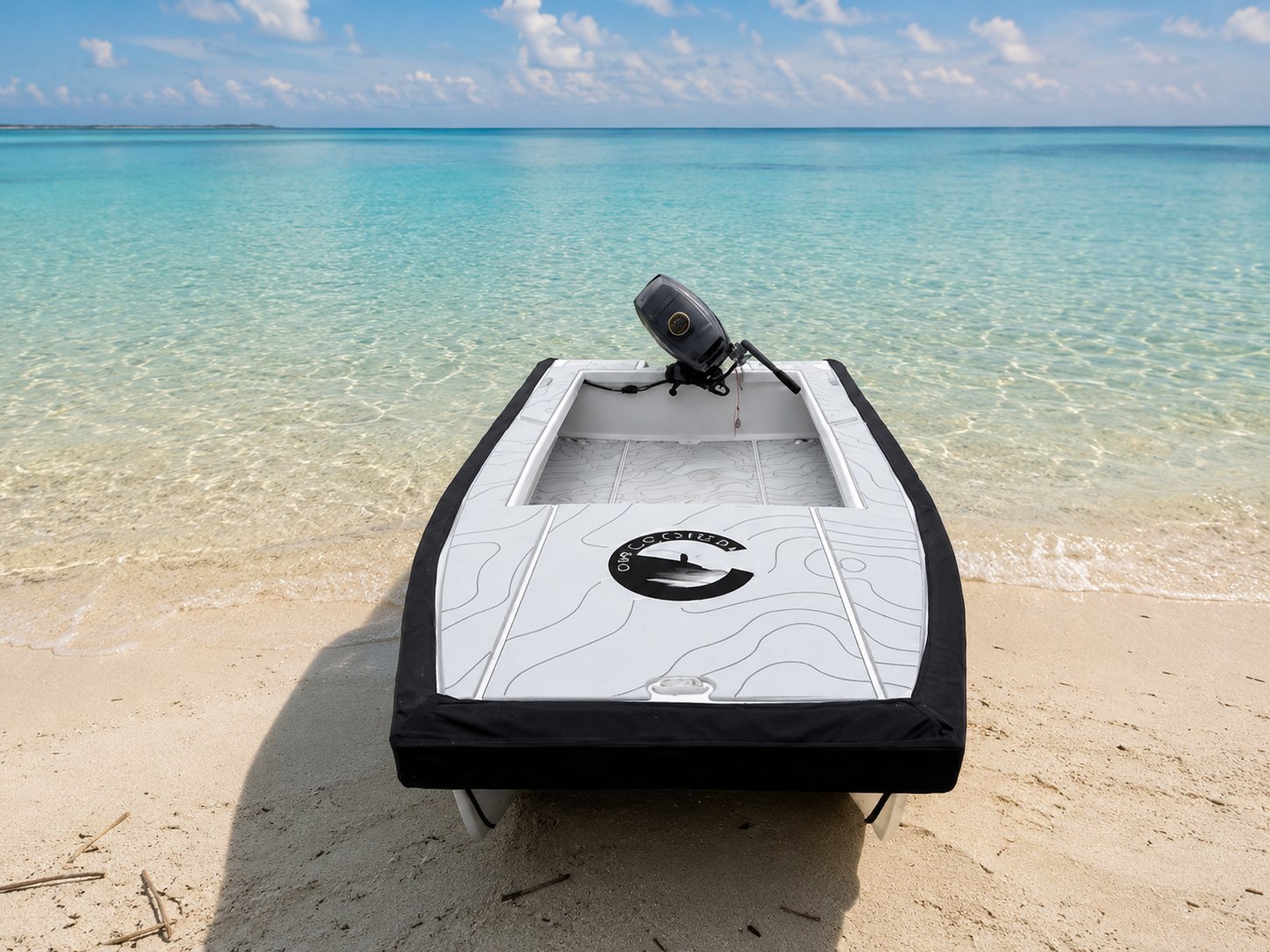 The Cape Cat 115 bow-on at the water’s edge on a white-sand beach, black wrap-around fender and non-skid foredeck in view, the outboard on the transom and turquoise shallows beyond