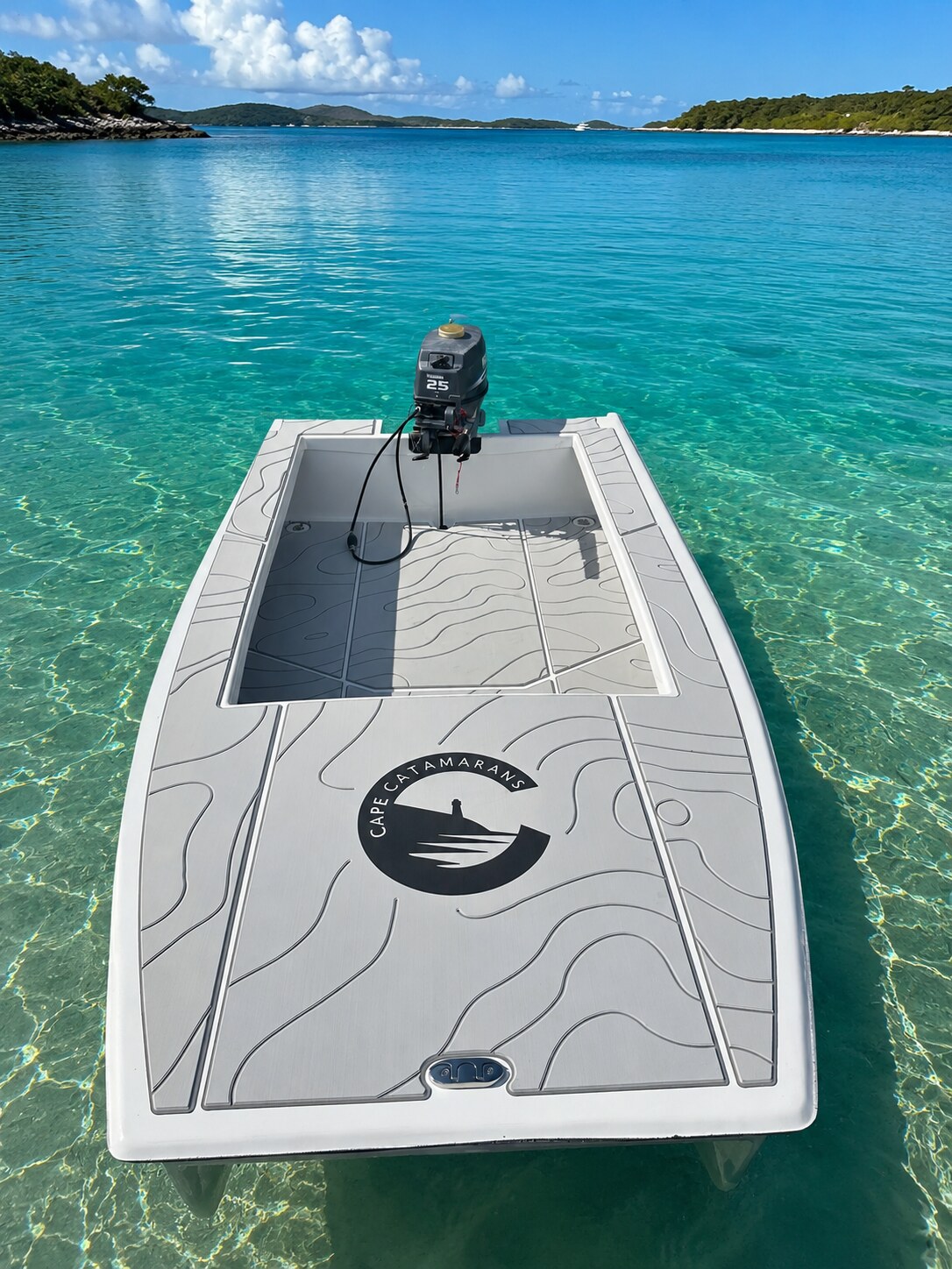 The Cape Cat 115 afloat over clear turquoise water, bow deck in the foreground and the outboard beyond